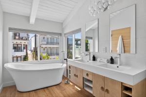 マンハッタン・ビーチにあるYour Coastal Getaway in Manhattan Beach Awaitsのバスルーム(大きな白いバスタブ、大きな鏡付)