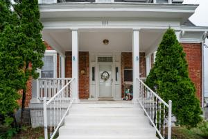 a white front door of a brick house with a christmas tree at Central 4BR Historic Gem Near Colleges in Lynchburg