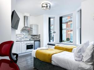 a white room with two beds and a kitchen at Comfy Contractor and Holiday Studio - Sleeps 2 in Coventry