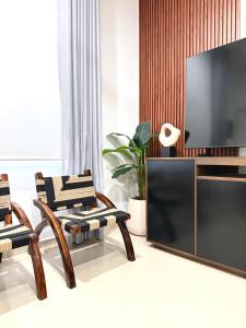 a living room with a flat screen tv and chairs at Encanto de Playa Sur By GEstores in Mazatlán