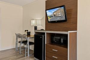 a hotel room with a desk and a tv on a wall at Heritage Inn Express Roseville in Roseville