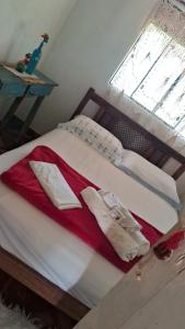 a bed with red and white sheets and a window at Ohana pouso campestre e camping in Tiradentes +6 photos