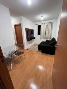 a living room with a black couch and a television at Ap em ótima localização in Cuiabá
