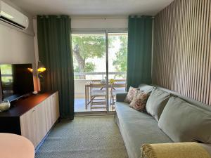 a living room with a couch and a sliding glass door at L'appartement Vert, Piscine, 750m de la Plage in Cavalaire-sur-Mer