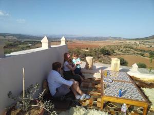 a man and a woman and a child sitting on a wall at 1001-Nights Palace in Nebeur