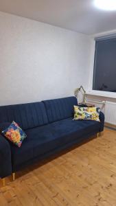 a blue couch in a living room with two pillows at Cozy studio apartment in Marijampolė +2 photos