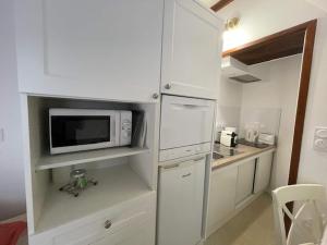 a kitchen with white cabinets and a microwave at Cottage in Central Bayeux in Bayeux