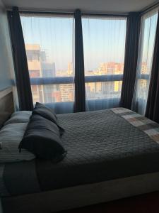 a bedroom with a bed with pillows and a large window at Never Give Up Suites in Santiago