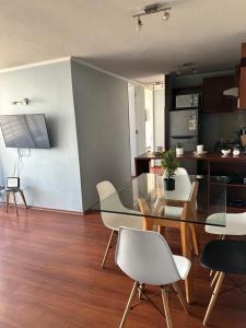 a dining room with a glass table and white chairs at Never Give Up Suites in Santiago