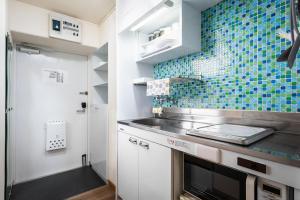 a small kitchen with a sink and blue tiles on the wall at 泉音屋 in Fukuoka
