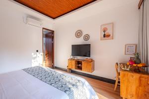 a bedroom with a bed and a flat screen tv at Cabaña de piña dulce ubud in Ubud