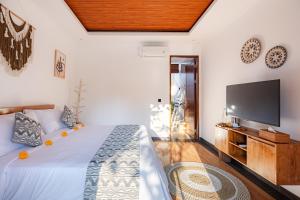 a bedroom with a bed and a flat screen tv at Cabaña de piña dulce ubud in Ubud +11 photos