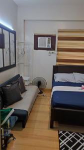 a bedroom with two beds and a couch and a microwave at Low-key Suites Trees Residences in Manila