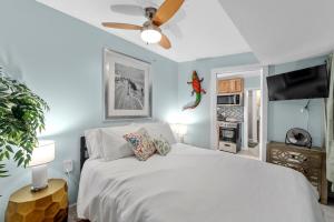 Un dormitorio con una cama blanca y un ventilador de techo. en Cozy Beach Getaway with Bikes included!, en St Pete Beach