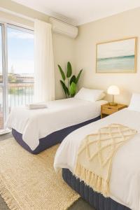 two beds in a bedroom with a window at Waterfront bliss, spacious corner block in Mandurah