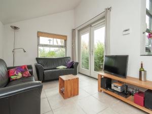 a living room with a couch and a television at Holiday Home in Schoorl near Dunes in Schoorl