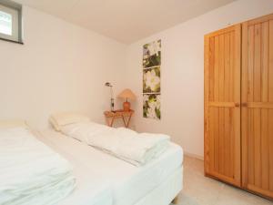 1 dormitorio con cama con sábanas blancas y puerta de madera en Holiday Home in Schoorl near Dunes, en Schoorl