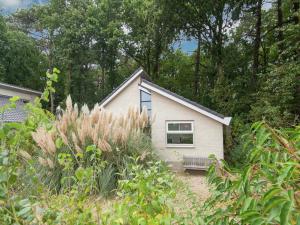 a small white house with a bench in a yard at Holiday Home in Schoorl near Dunes in Schoorl