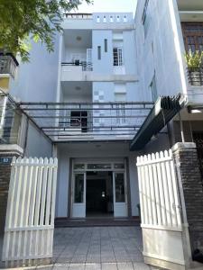 a white house with a white fence and a building at Cozy Dormitory House in Da Nang
