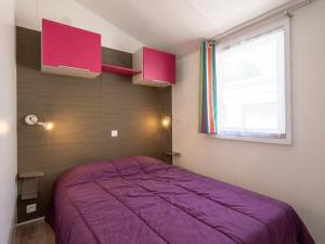 a bedroom with a purple bed and a window at Mobil home 2 chambres avec terrasse - API-1-52-478 in Brétignolles-sur-Mer +20 photos