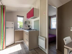 a small kitchen with a stove and a refrigerator at Mobil home 2 chambres avec terrasse - API-1-52-478 in Brétignolles-sur-Mer