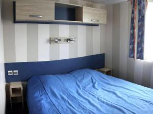 1 dormitorio con cama azul y manta azul en Mobil home 32m² avec terrasse pour 6 personnes - API-1-52-386, en Bretignolles-sur-Mer 26 fotos más
