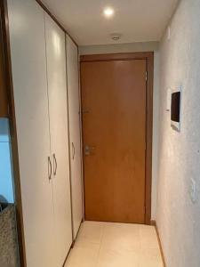 Un pasillo con una puerta de madera en una habitación. en Flat Saint Moritz, en Brasilia