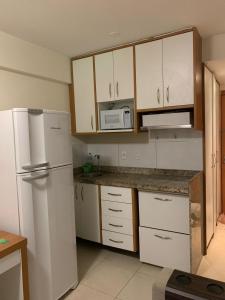 Una cocina con gabinetes blancos y un refrigerador blanco. en Flat Saint Moritz, en Brasilia