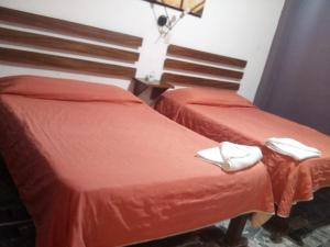 Dos camas en una habitación con sábanas rojas y zapatillas blancas. en Hotel Viña del Mar, en Lázaro Cárdenas