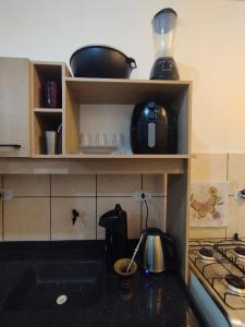 a kitchen with a stove and a shelf with pots and pans at Apartamento 2 quartos in Cascavel