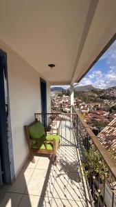a green chair sitting on a balcony with a view at Escadaria Vila Rica Pousada & Hostel in Ouro Preto
