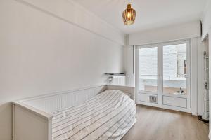 a white bedroom with a bed and a window at Casa Améo in Ostend +1 photo