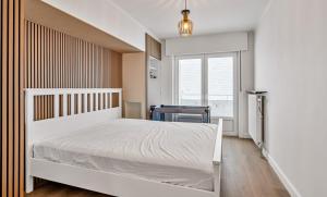 a bedroom with a white bed and a window at Casa Améo in Ostend