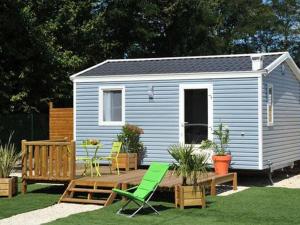 a small blue shed with a deck and chairs at Mobil-home cosy avec terrasse à Avrillé - API-1-52-490 in Avrillé
