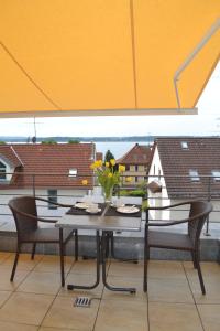 a table with chairs and a vase of flowers on a balcony at Ferienwohnungen Rothmund in Uhldingen-Mühlhofen