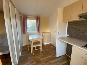 a small kitchen with a table and a dining room at Mobil-home cosy avec terrasse pour 2 personnes - API-1-52-575 in Le Fouilloux