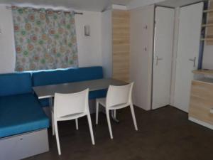 une chambre avec une table, des chaises et un canapé bleu dans l'établissement Mobil home confortable avec terrasse et équipement complet - API-1-52-601, à Limeuil