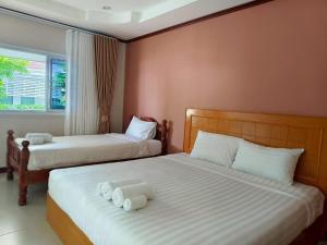 a bedroom with two beds with white sheets and a window at บุรีสอร์ต บุรีรัมย์ Burisort Burirum in Buriram