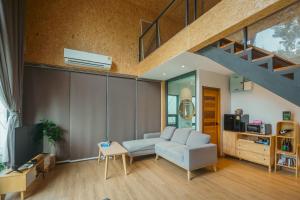 Una sala de estar con un sofá y una escalera. en The X10 private pool villa khaoyai SHA Certified เขาใหญ่, en Ban Tha Chang