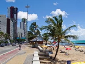 uma praia com cadeiras e guarda-sóis e o oceano em Flat em Boa Viagem no Recife