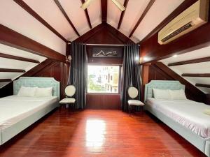 two beds in a room with a window at GemVilla 188 Large pool garden in Ho Chi Minh City