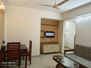 a living room with a couch and a table and a tv at Platinum Airport Lounge by VVP in Nedumbassery