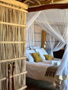 a bedroom with a canopy bed with white sheets and yellow pillows at ENTREMER Maison du bout du monde in Belo +34 photos