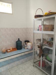 a kitchen shelf with dishes and pots and pans at Cozy Corner House in Banyuwangi