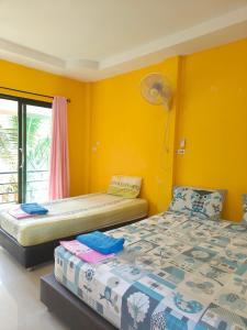 two beds in a room with yellow walls at No Name Bungalow Haad Yao in Haad Yao