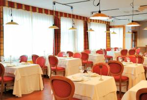 una sala da pranzo con tavoli bianchi e sedie rosse di Grand Hotel la Chiusa di Chietri ad Alberobello