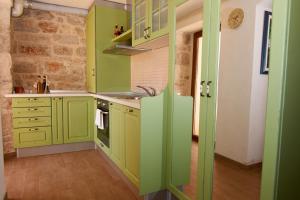 a kitchen with green cabinets and a sink at Dalmatian Stone House in Krapanj