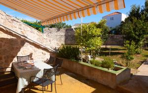 um pátio com uma mesa e cadeiras debaixo de um guarda-sol em Dalmatian Stone House em Krapanj