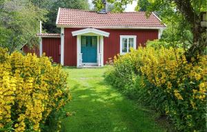 a red cottage with a blue door and yellow flowers at 2 Bedroom Gorgeous Home In Malmbäck in Malmbäck