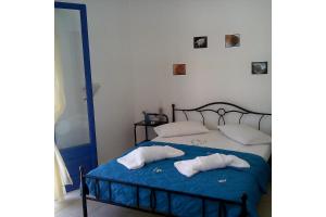 a bedroom with a bed with blue sheets and white pillows at Vigles in Adamantas